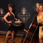 in 20er Jahren fashion - flapper kleidern und kopfschmuck- posieren die beiden musikerinnen der 20er jahre band