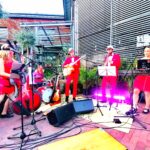 In rot gekleidete Musiker*innen, die Open Air gerade bei der Konzertreihe 100 Jahre Jazz&Pop auftreten.